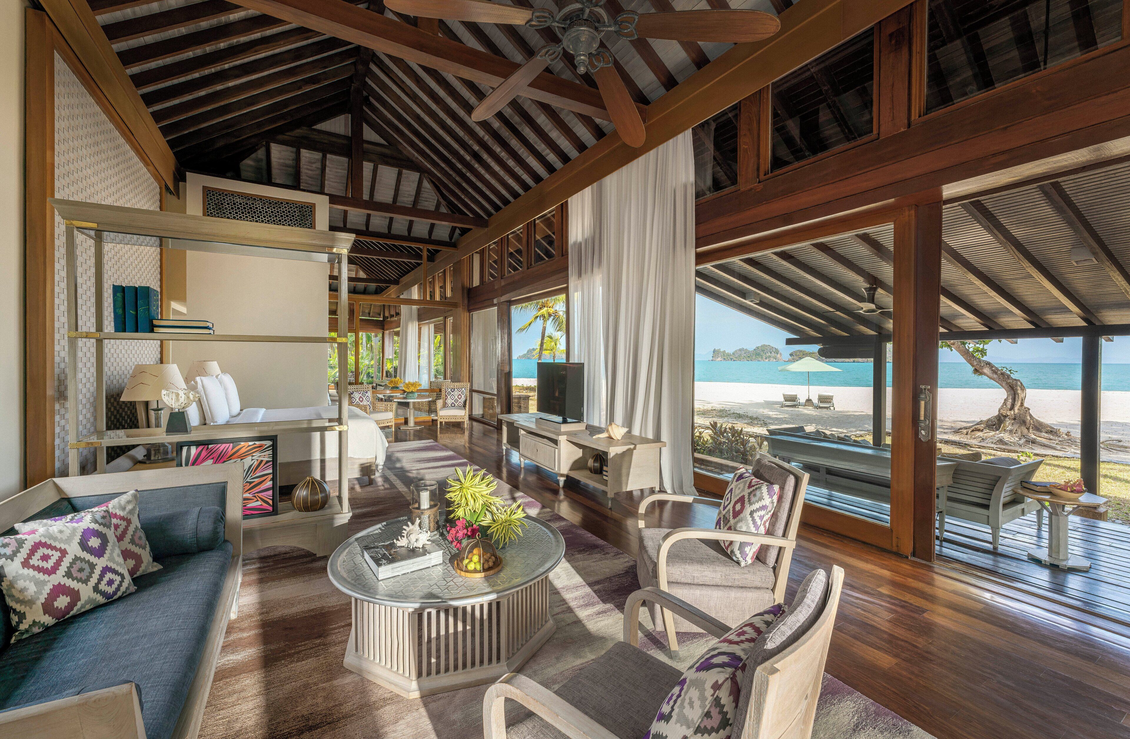 A spacious living room with a large TV, comfortable seating, and a view of the beach.