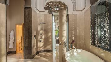 A luxurious bathroom with a large bathtub, a shower area, and a wooden door leading to a staircase.