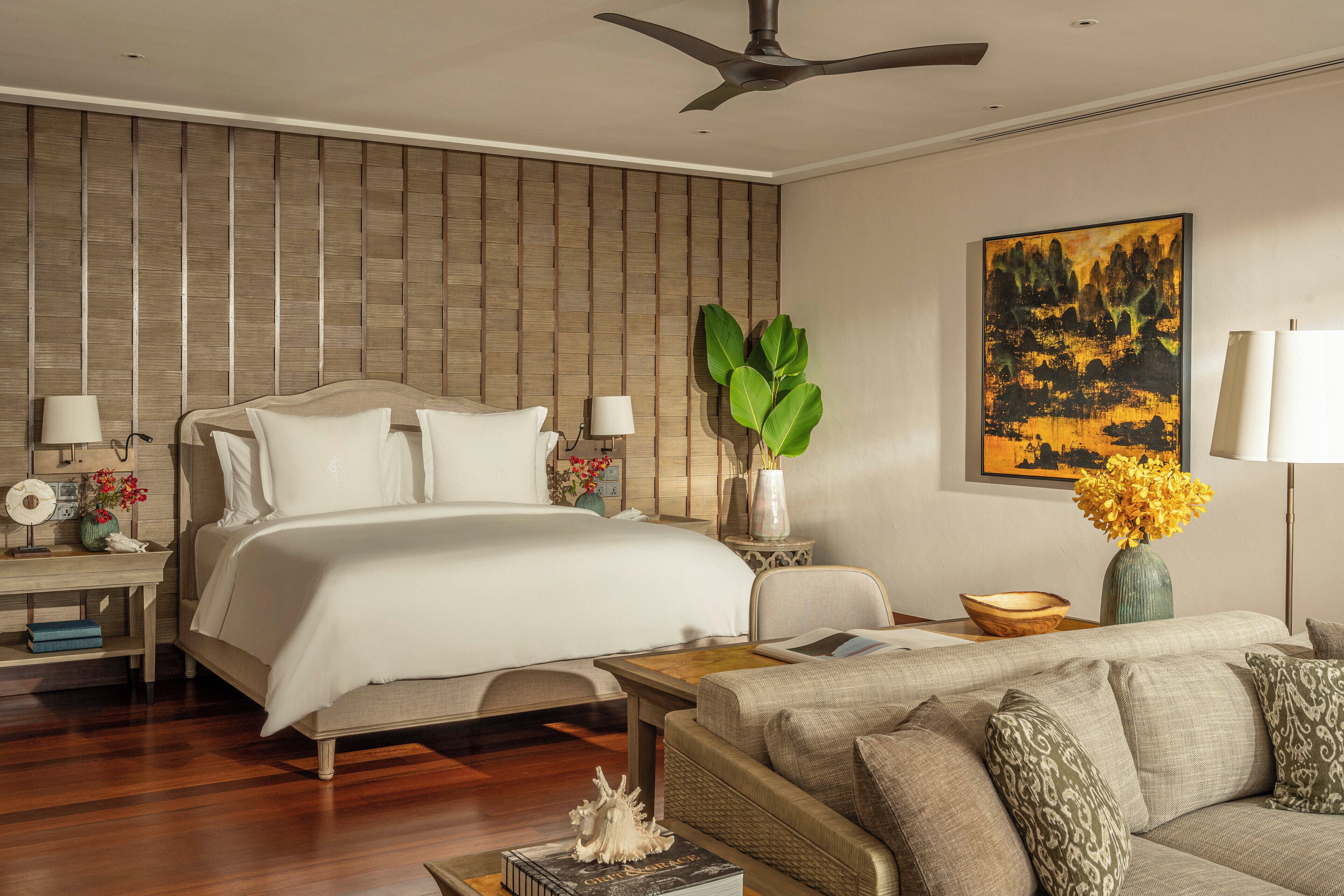 Une chambre d’hôtel moderne avec un grand lit, un canapé, une table basse et un tableau accroché au mur.