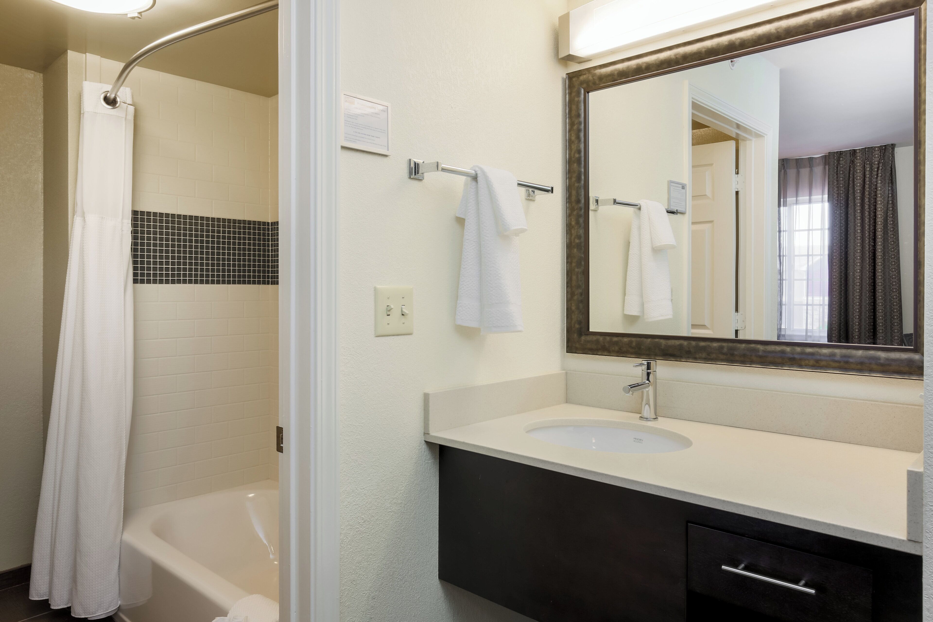 A bathroom with a bathtub, a sink, a mirror, and a shower curtain.