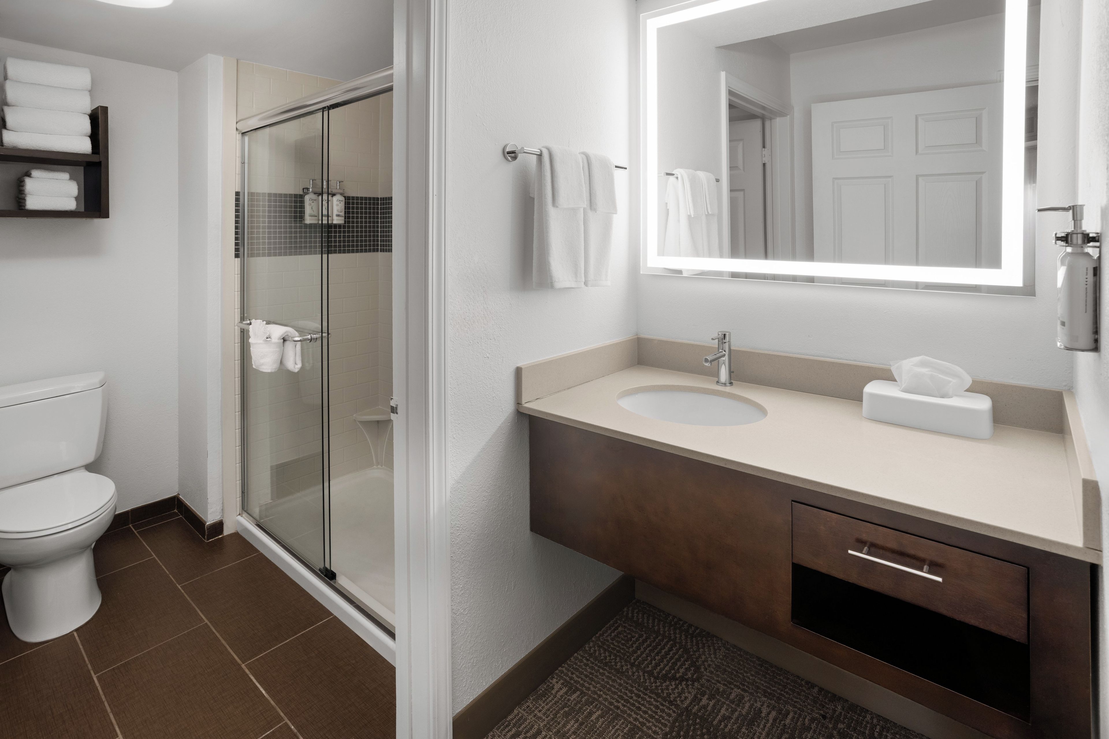 A modern bathroom with a toilet, shower, sink, and mirror.