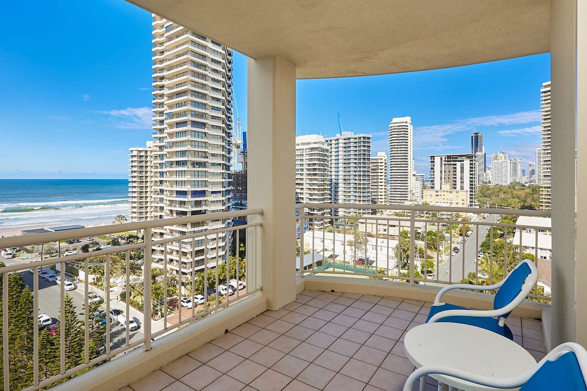 A balcony with a view of the ocean and cityscape.