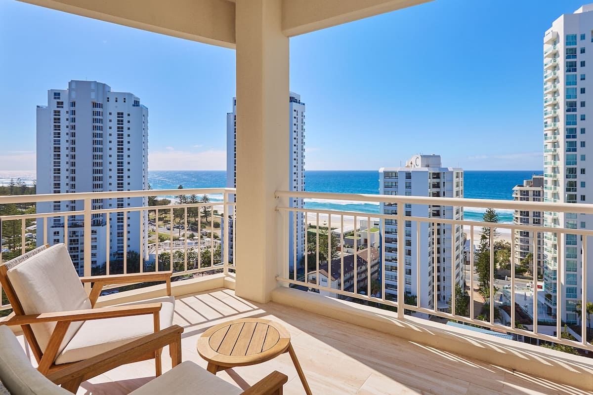 A balcony with a view of the ocean and high-rise buildings.