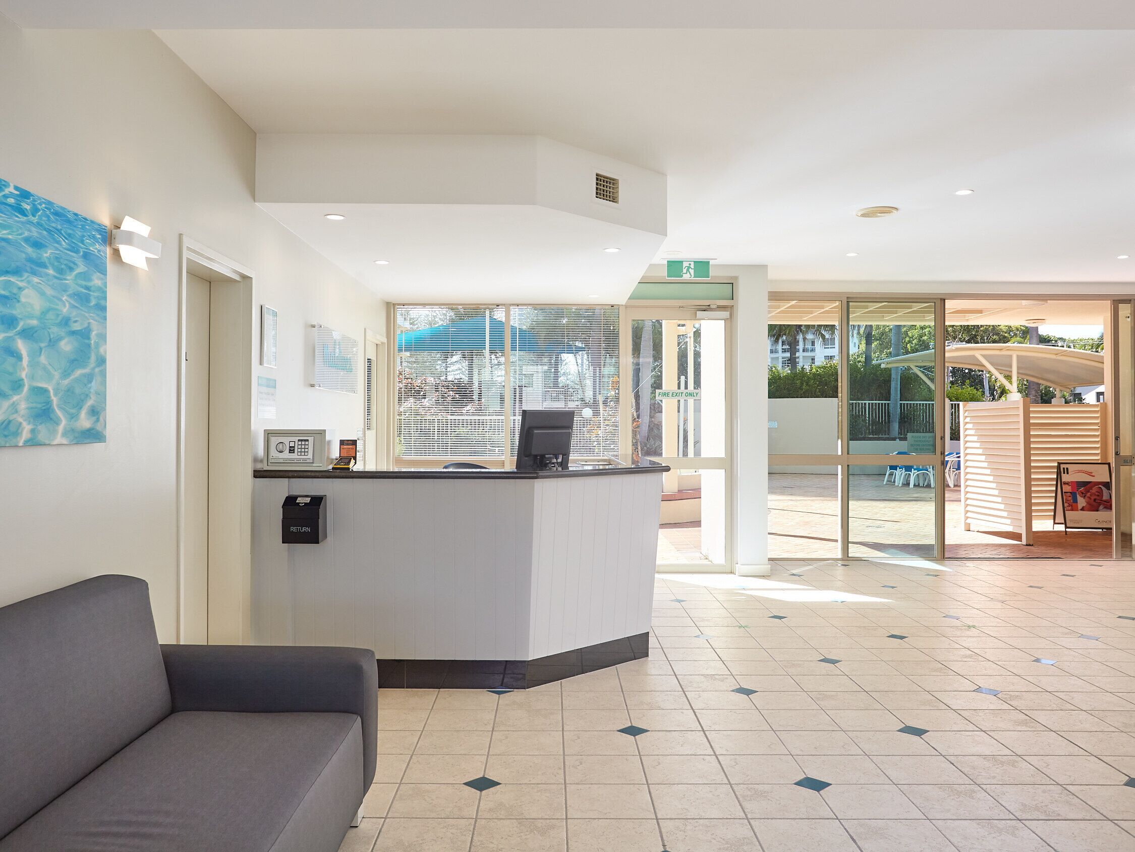 A reception area with a sofa, a reception desk, and a glass door leading outside.