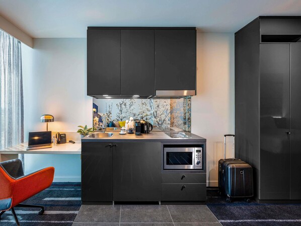 A compact kitchenette with a microwave, coffee maker, and a small sink. - Novotel Melbourne Preston (Preston)