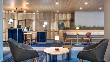 Un área de estar moderna con techo de madera, un mostrador de recepción, arreglos de asientos e iluminación ambiental.