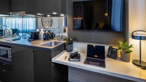 A modern kitchen with a built-in microwave, a sink, and a countertop with a laptop, a phone, and a plant. - Novotel Melbourne Preston (Preston)