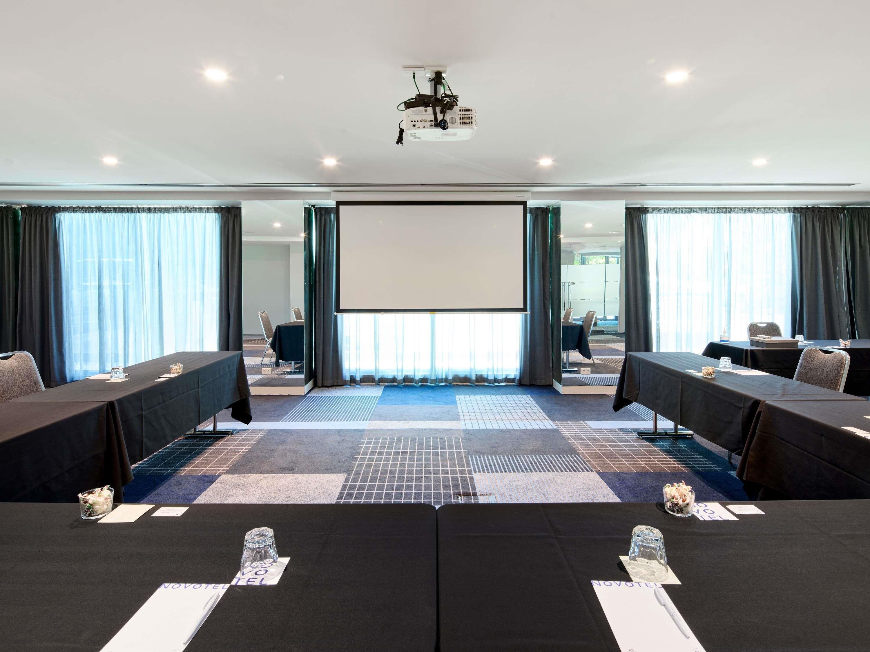 A conference room with a large screen, tables with name placards, and a projector.