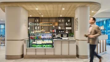 Een modern café met een glazen vitrine, een houten plafond en een bord met de tekst 'STAMPTON COFFEE'.