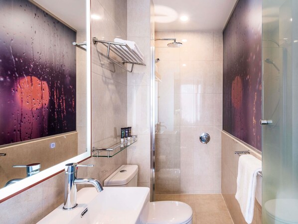 Un baño moderno con cabina de ducha de vidrio, un lavamanos blanco y un inodoro.