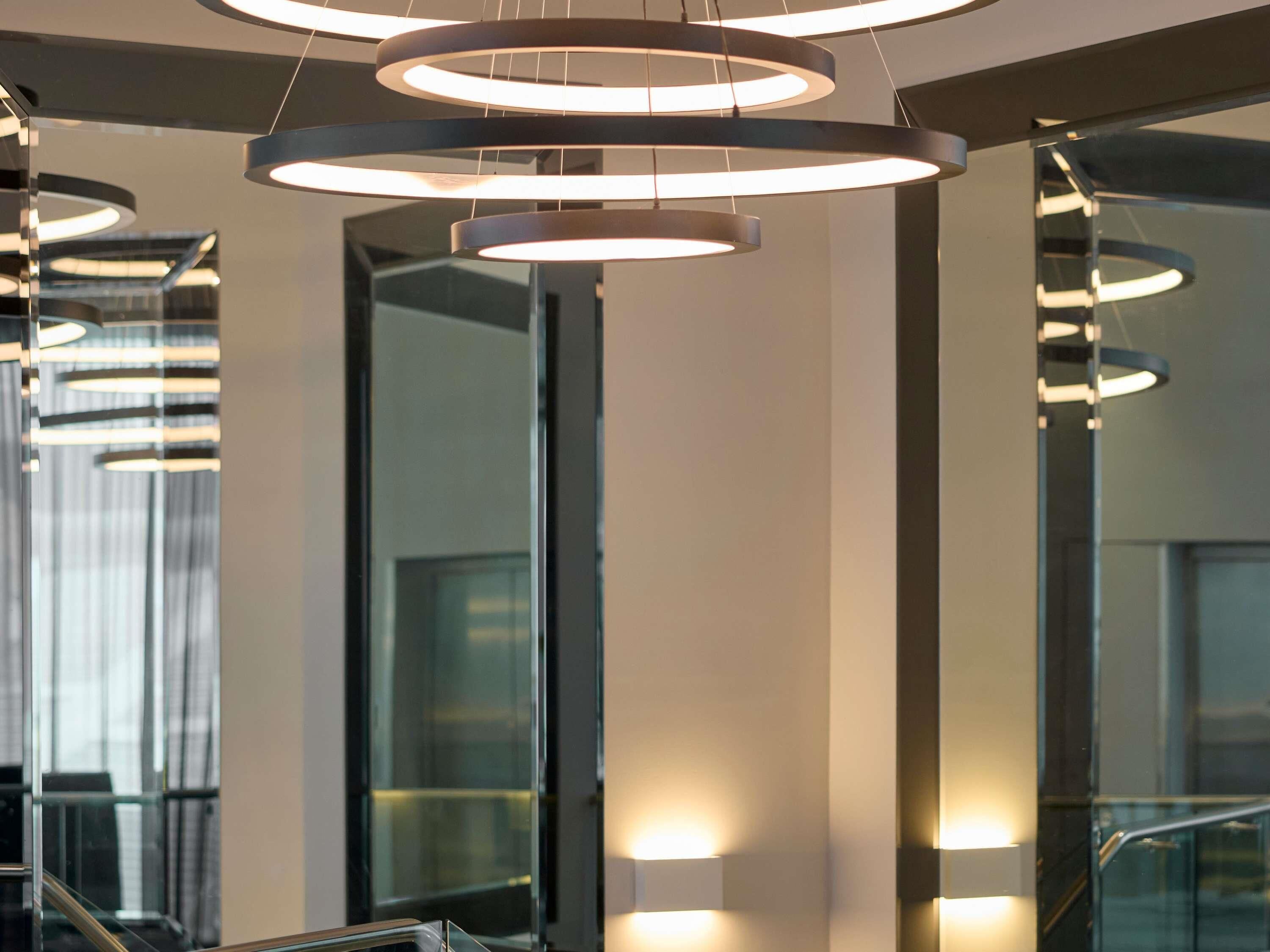 A modern interior with circular light fixtures, glass railings, and a reflective surface.
