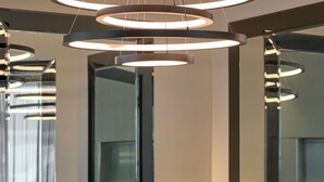 A modern interior with circular light fixtures, glass railings, and a reflective surface. - Novotel Melbourne Preston (Preston)