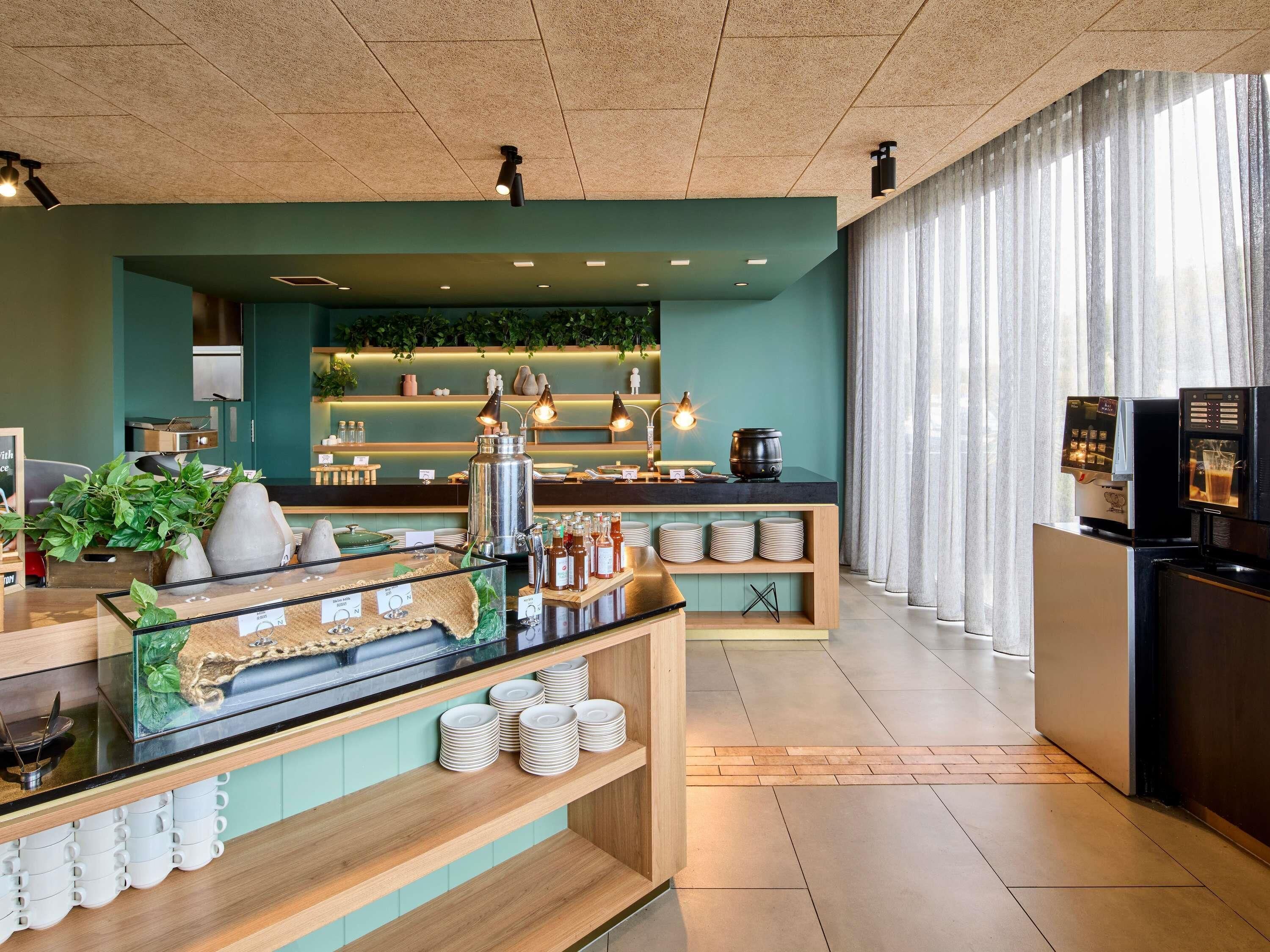 A modern hotel lobby with a coffee bar, seating area, and a view of the city.