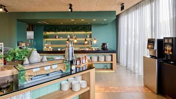 Un moderno vestíbulo de hotel con una barra de café, zona de estar y vistas a la ciudad.