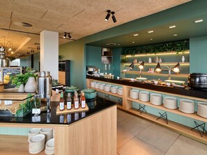 A buffet setup with various food items and condiments, a coffee machine, and a sign promoting upgraded buffet breakfast. - Novotel Melbourne Preston (Preston)