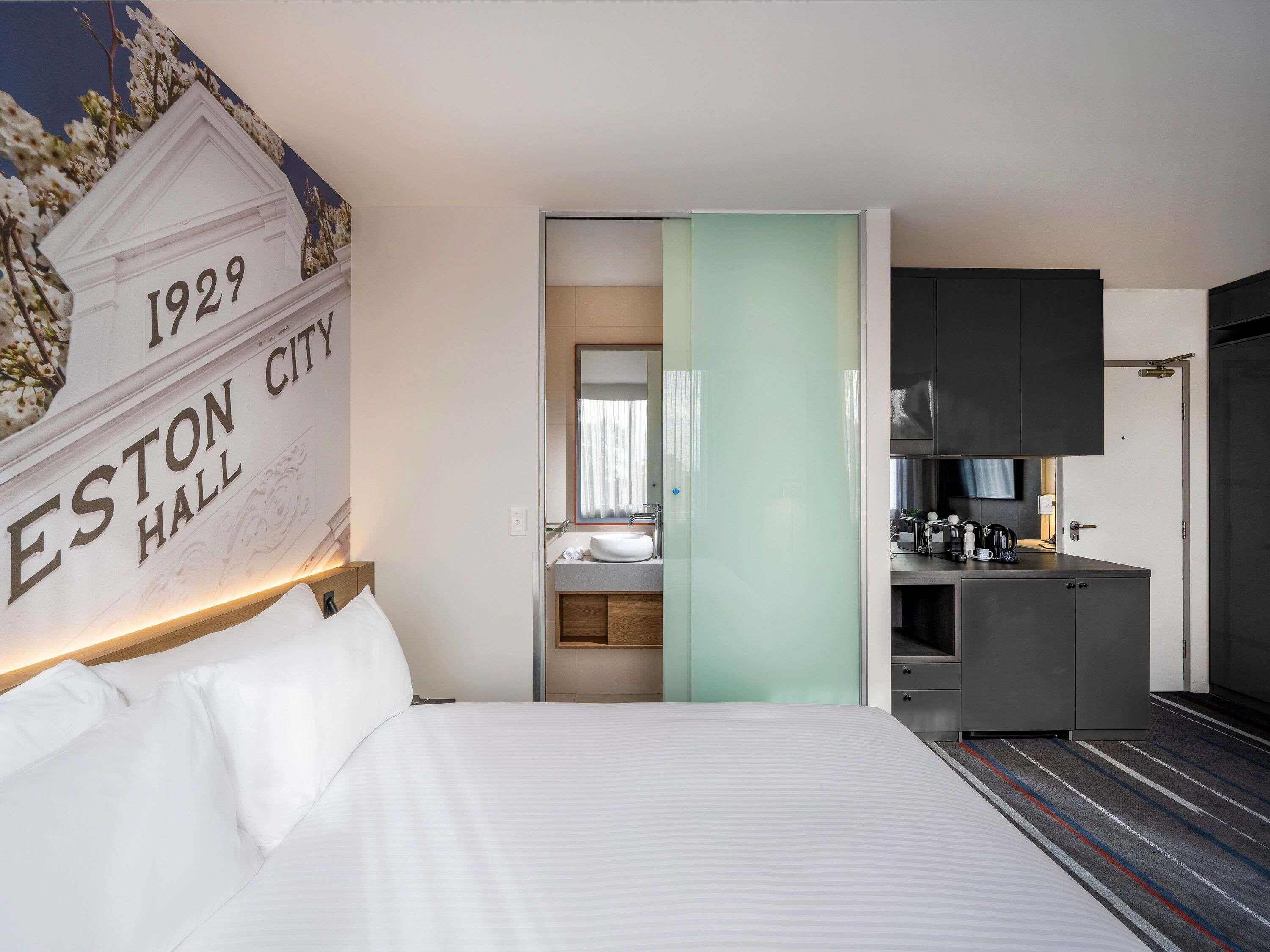 Ein Hotelzimmer mit Bett, Badezimmer mit Waschbecken und einer Küchenzeile.
