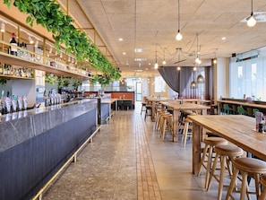 Un espace bar avec un comptoir, des tabourets et des plantes suspendues.