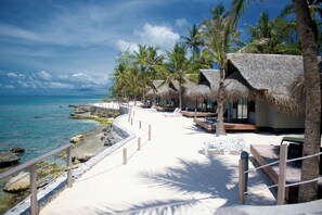 A beachside resort with thatched-roof huts, lounge chairs, and a clear view of the ocean. - Le Maitai Rangiroa (Rangiroa)