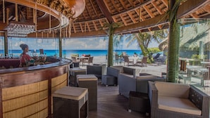 A beachside bar with wicker furniture and a view of the ocean.