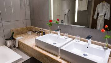 A bathroom with two sinks, a bathtub, a vanity with toiletries, and a large mirror.