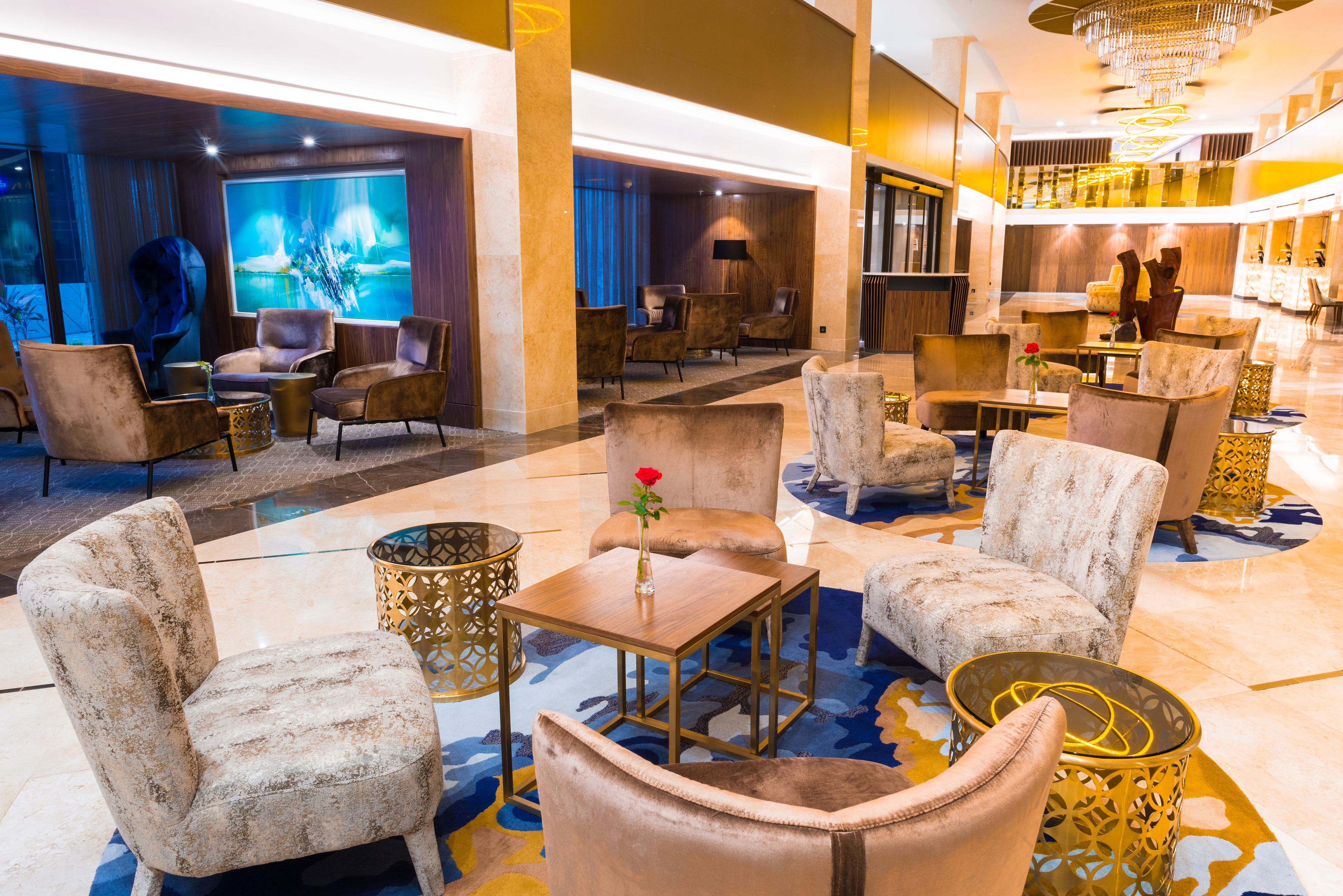 A spacious lobby with plush seating, a large screen, and a chandelier.