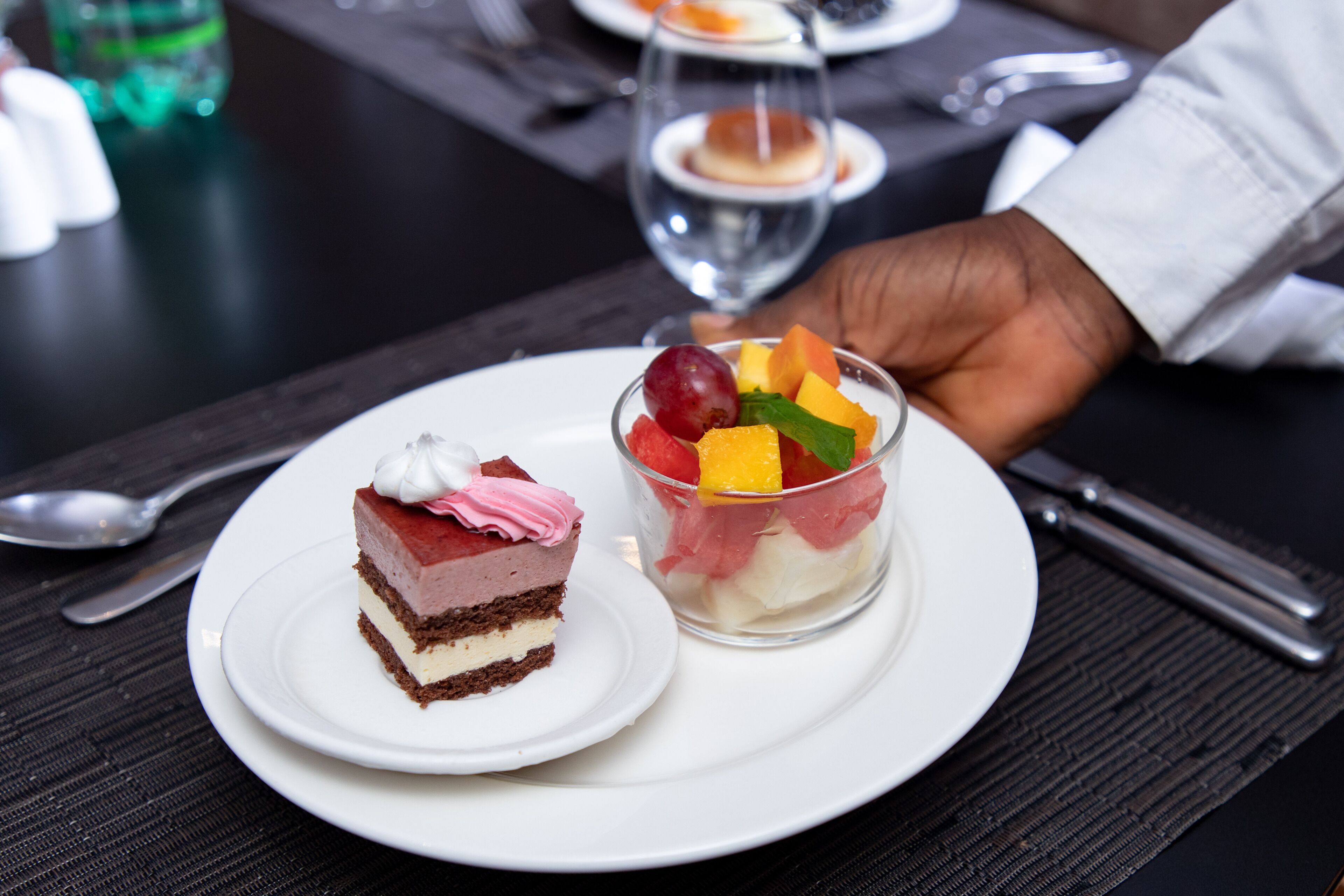 A dessert plate with a slice of cake and a fruit parfait.