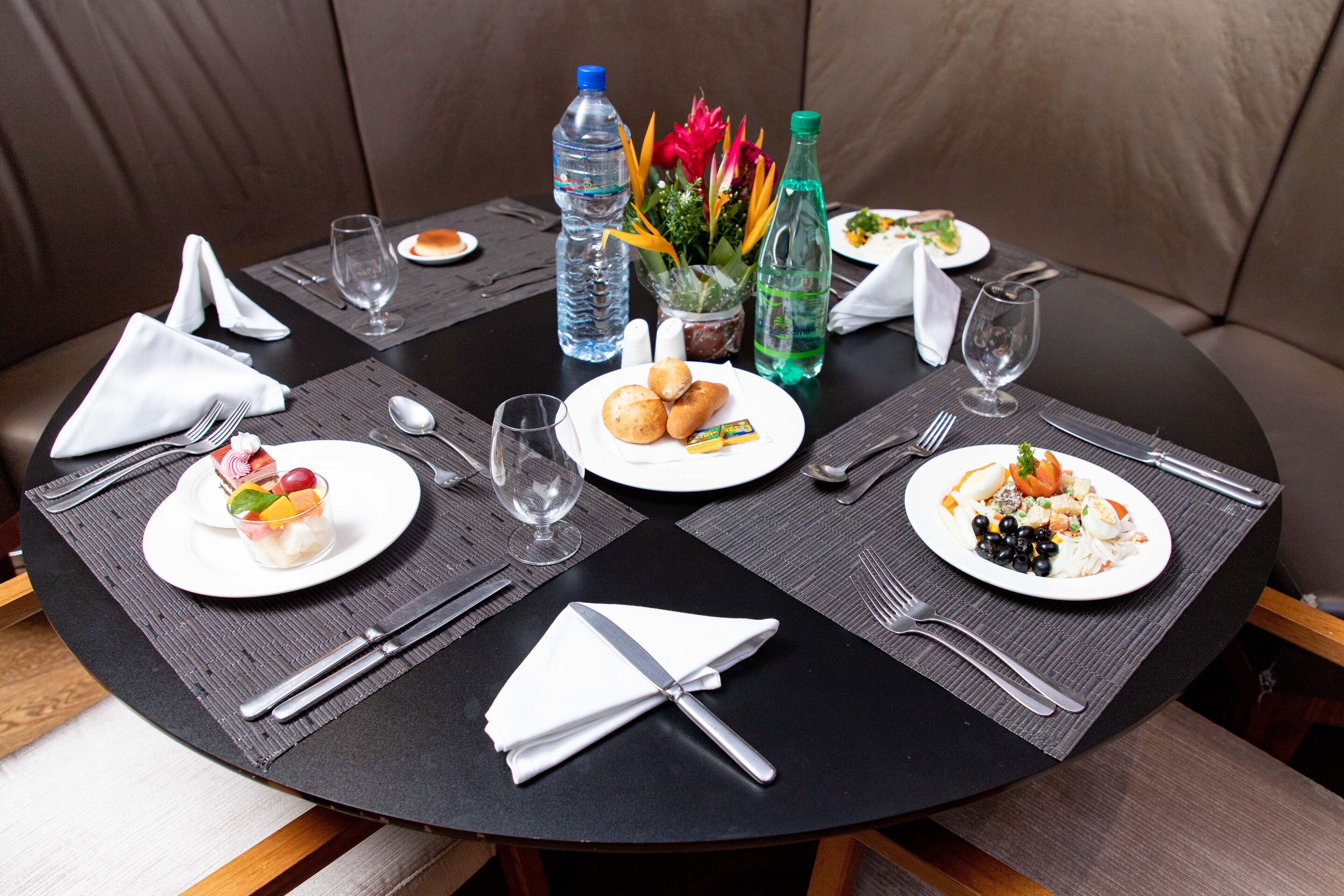 Een ronde eettafel met een zwart tafelkleed, omringd door bruine lederen zitplaatsen.
