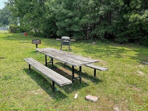 A picnic table with benches in a grassy area with trees in the background. - Motel 6 West Columbia, SC - Airport (West Columbia)