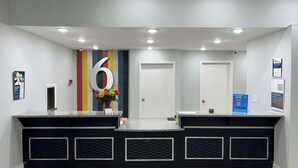 Un espace d’accueil avec un grand chiffre « 6 » affiché sur le mur, un vase de fleurs et un comptoir au motif noir et blanc.