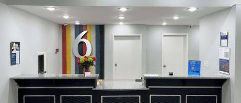 A reception area with a large number '6' on the wall, a flower vase, and a counter with a black and white design.