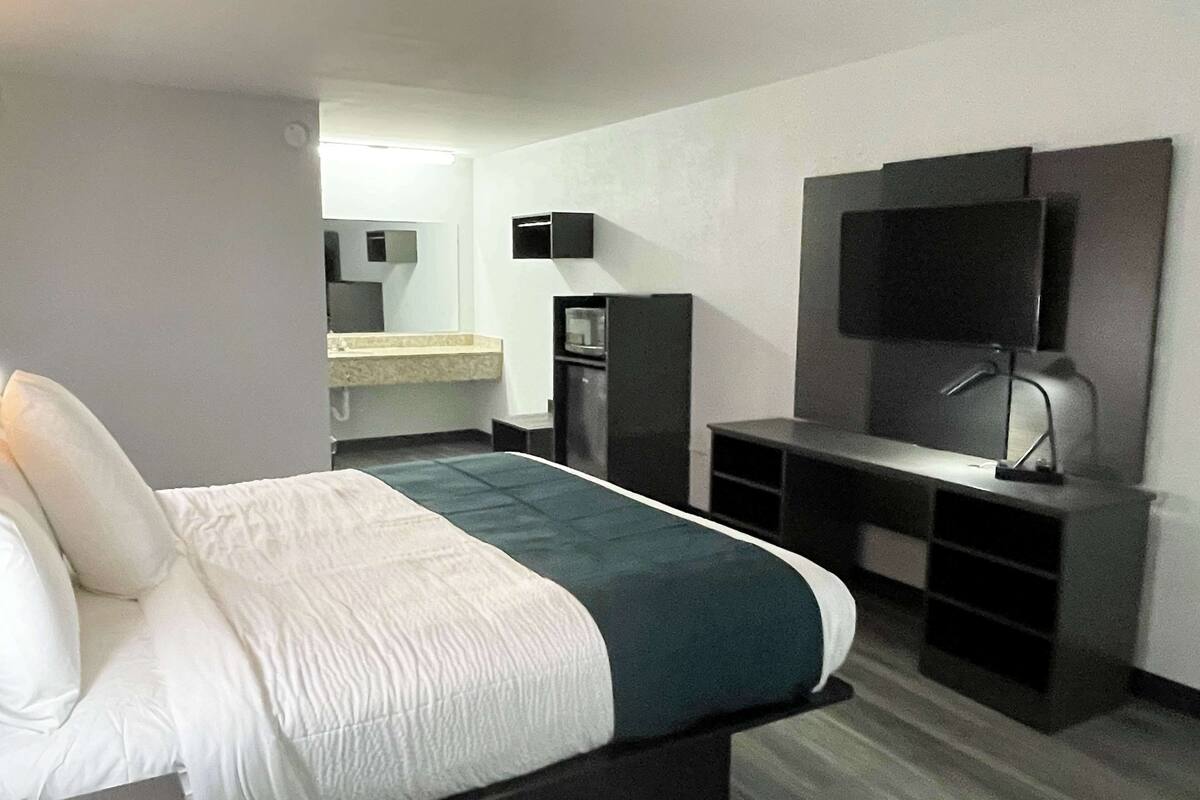 Een hotelkamer met een bed, een bureau, een televisie en een spiegel.