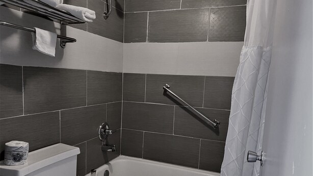 A modern bathroom with a bathtub, toilet, and a towel rack. - Rogers Inn (Rogers)