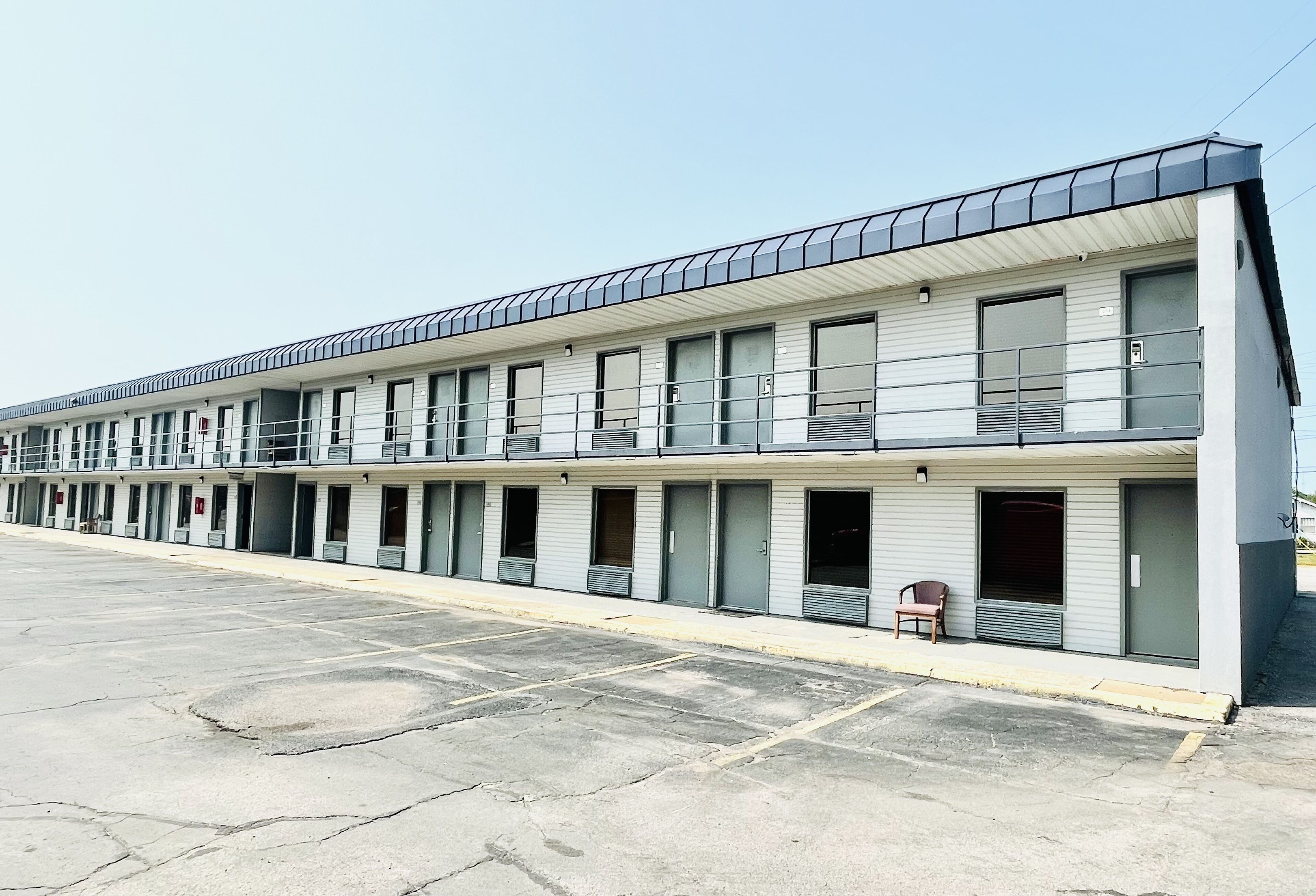 A motel with a row of rooms, each with a window and a door.
