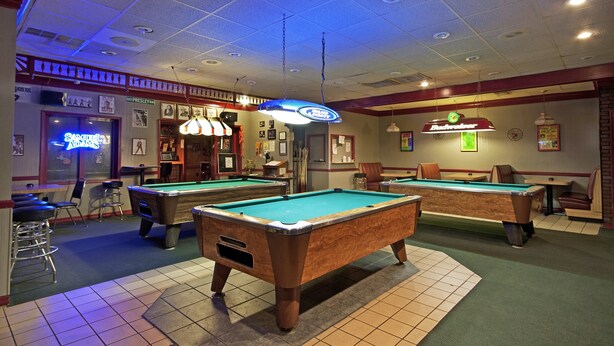 A pool hall with two pool tables, bar stools, and a neon sign. - Rogers Inn (Rogers)
