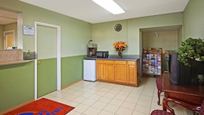 A compact kitchen with a refrigerator, microwave, and wooden cabinets. - Rogers Inn (Rogers)