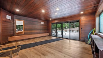 A wooden interior with a bench, a large window, and a view of an outdoor patio area.