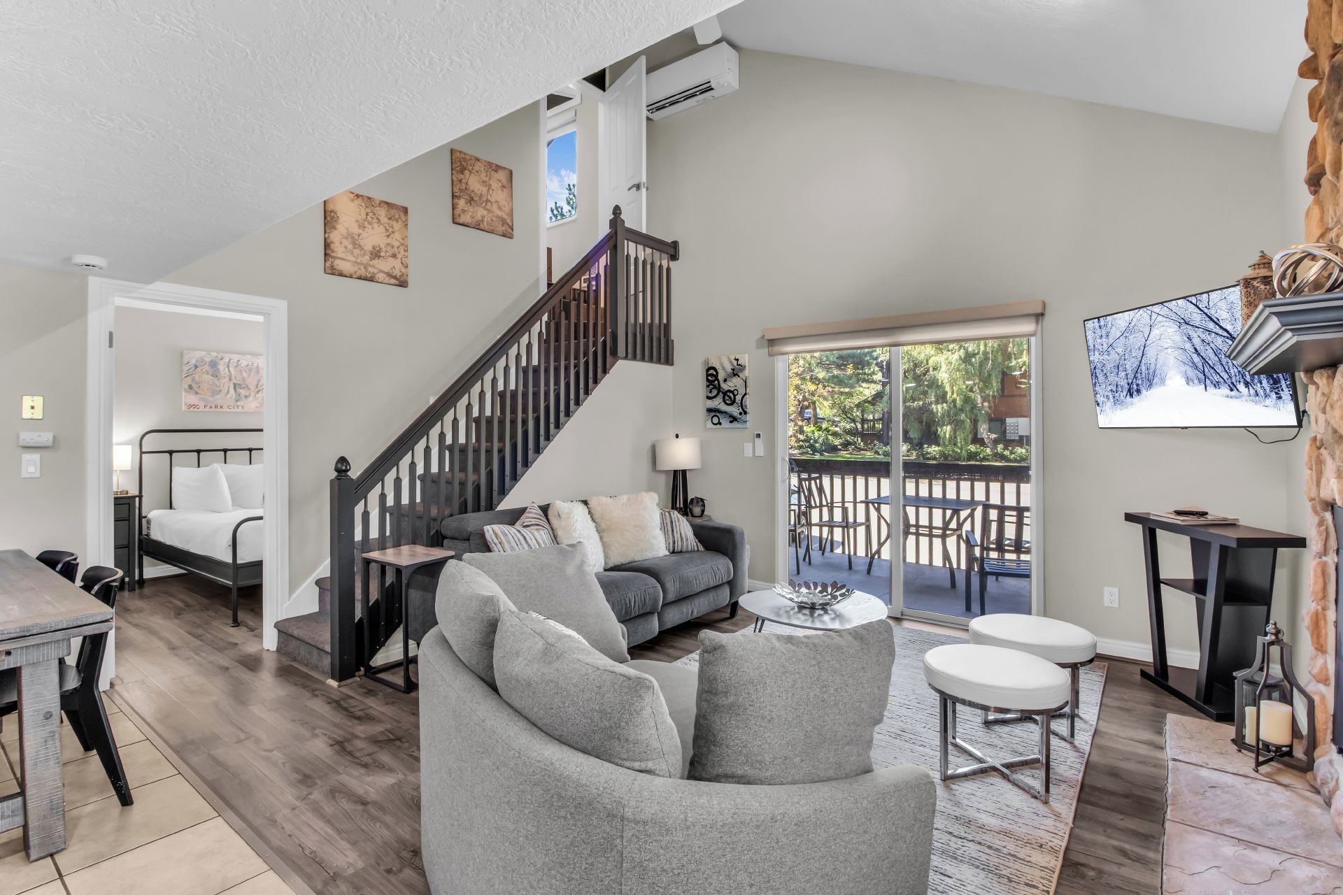 A spacious living area with a staircase, a sofa, a dining table, and a television.