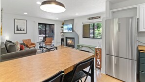 A modern kitchen with a built-in refrigerator, a dining table, and a fireplace. - Red Pine Condominiums by All Seasons Resort Lodging (Park City)