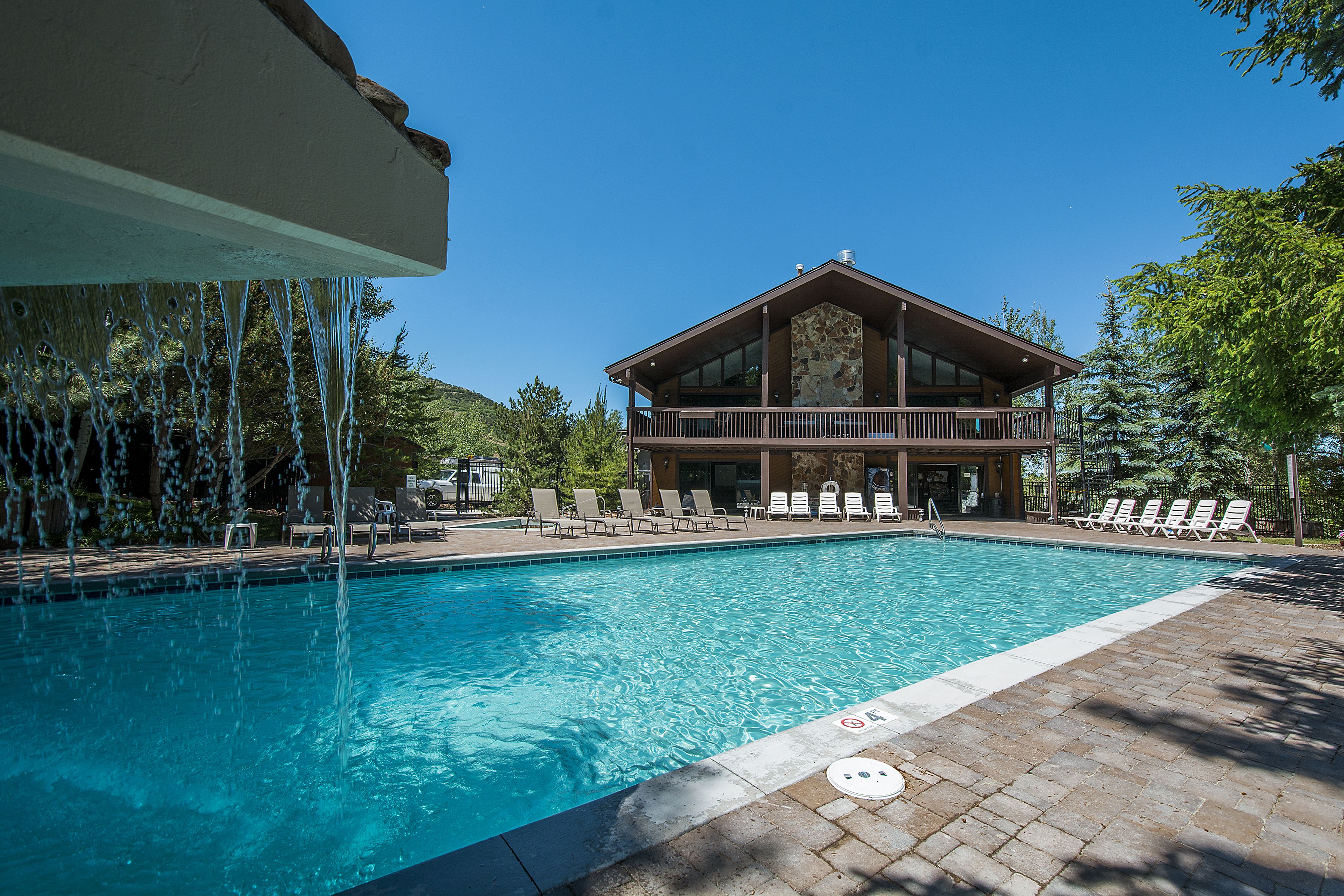 A swimming pool with lounge chairs and a building with a balcony.