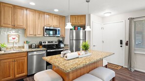 A modern kitchen with wooden cabinets, stainless steel appliances, granite countertops, and bar stools. - Red Pine Condominiums by All Seasons Resort Lodging (Park City)