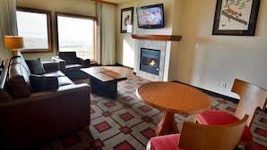 A living room with a fireplace, a television, and a large window overlooking a scenic view.