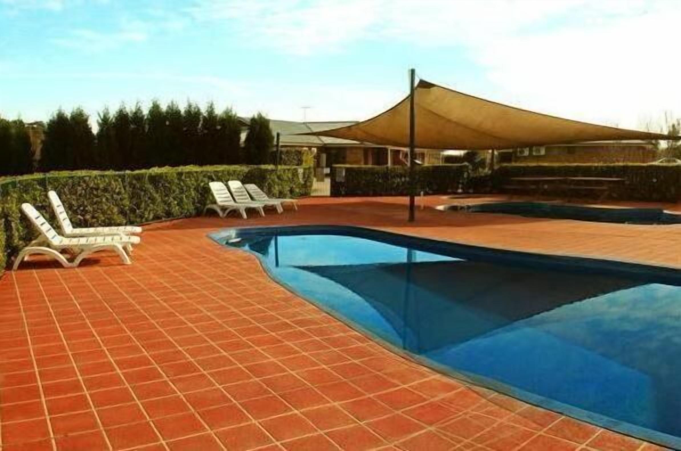 Una piscina con sillas de descanso y una zona cubierta.
