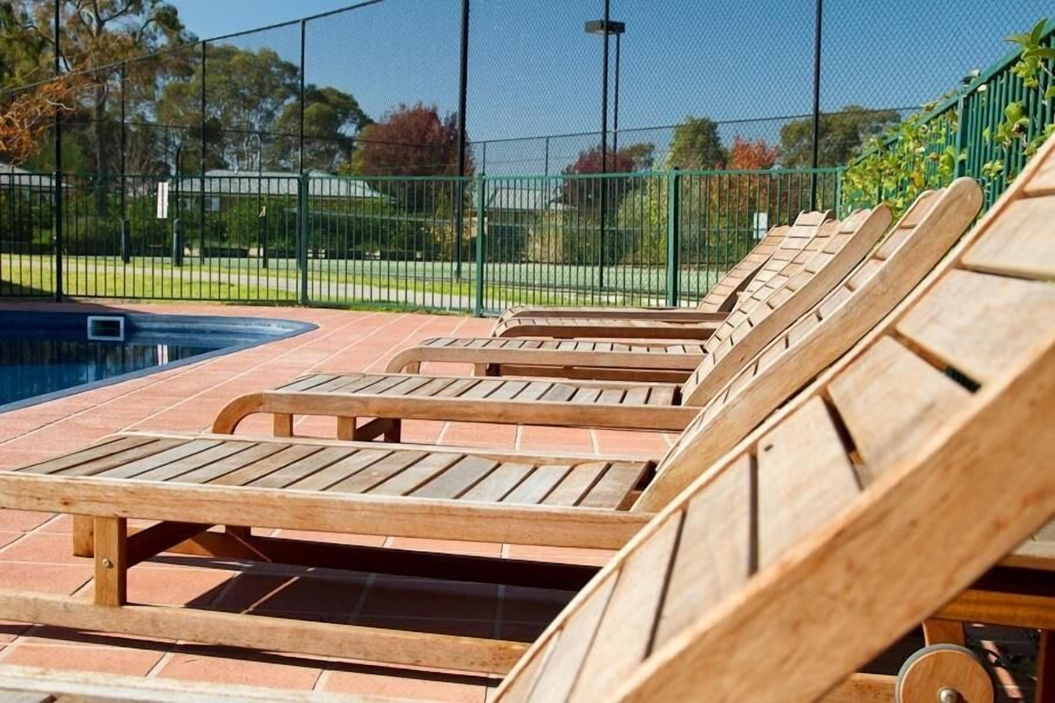A poolside area with wooden lounge chairs and a tiled deck.