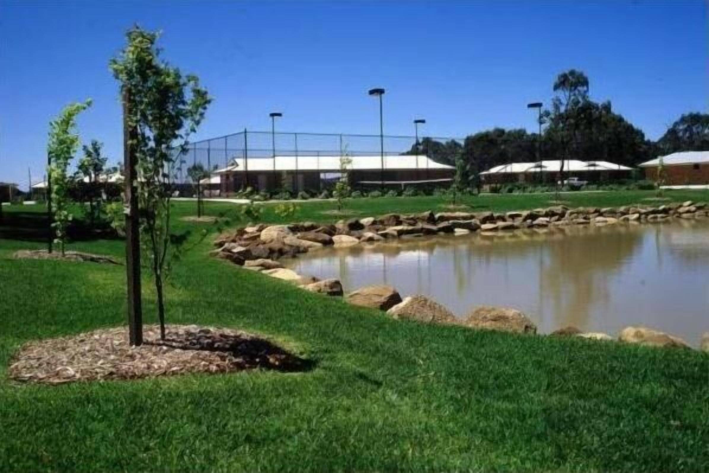 A landscaped area with a pond, rocks, and a fence.