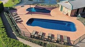 Une piscine avec des chaises longues et un petit bâtiment.