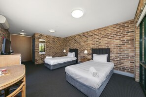 A hotel room with two beds, a desk, and a TV.