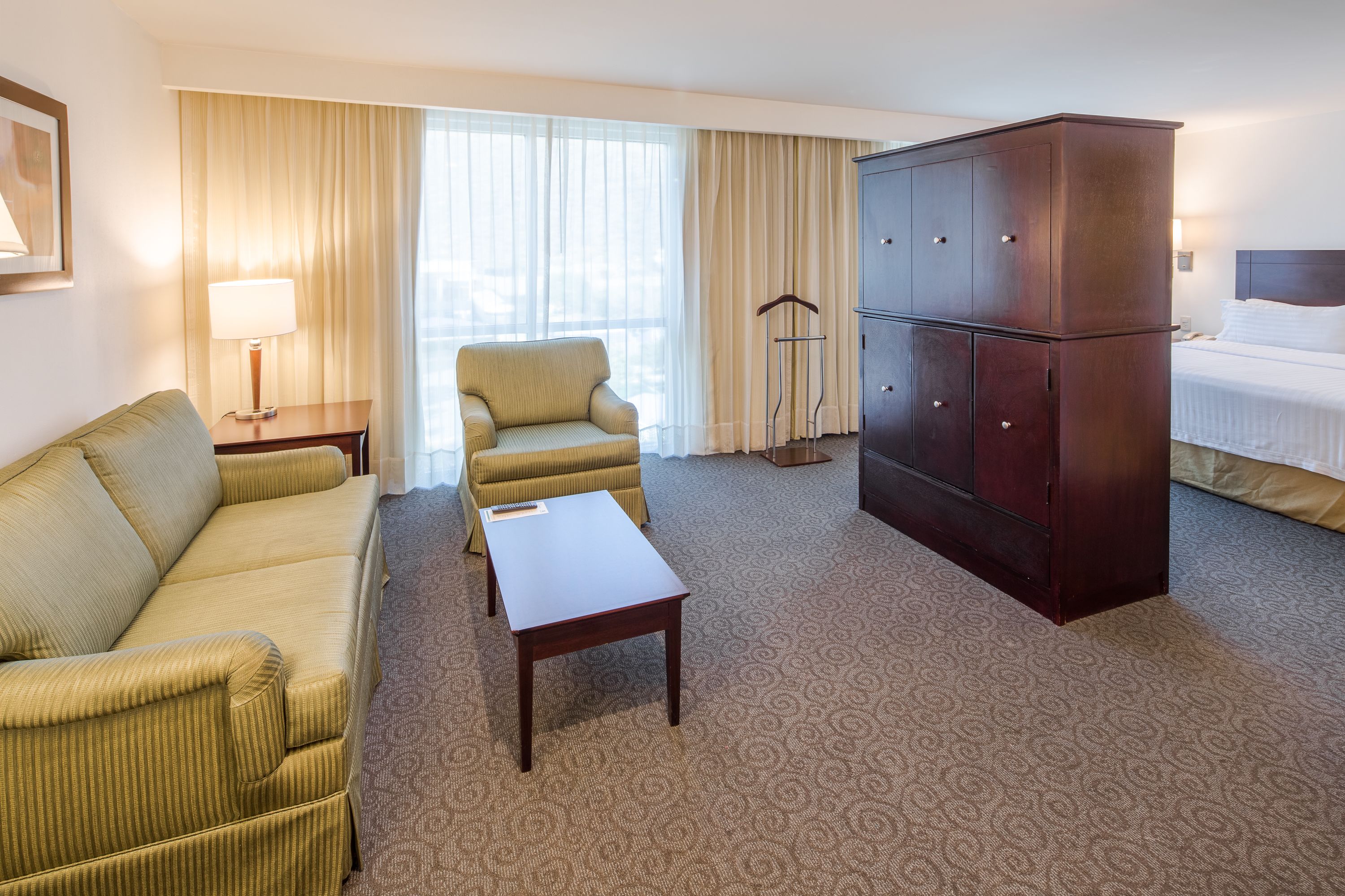Habitación de hotel con sofá, sillón, una mesita, armario y cama.