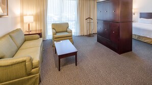 A hotel room with a sofa, armchair, a small table, a wardrobe, and a bed. - Holiday Inn Monterrey Valle by IHG (San Pedro Garza García)