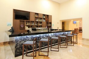 Zona de bar con encimera de mármol, taburetes y una televisión sobre la barra.