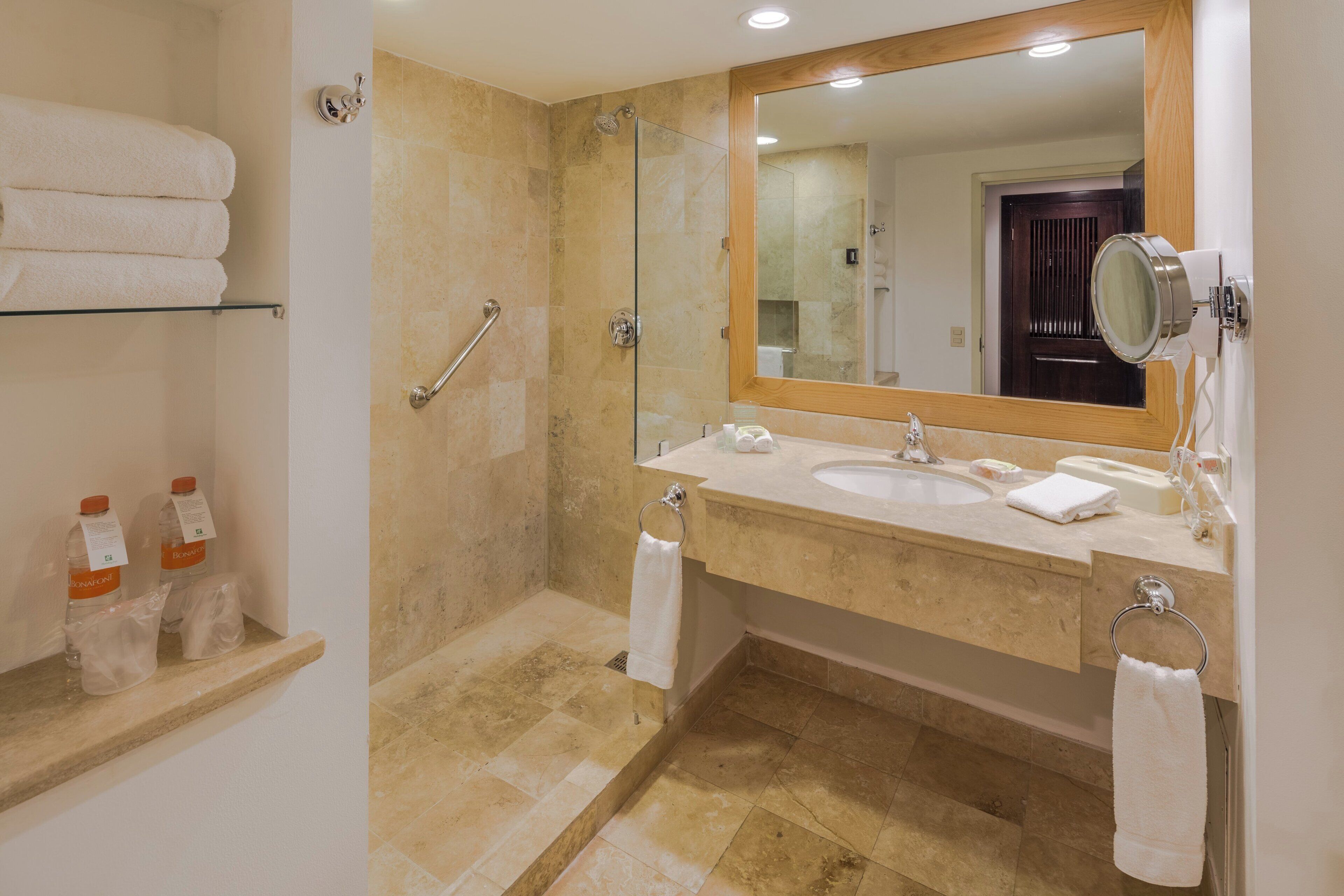 A bathroom with a glass shower enclosure, a vanity with a sink, and a mirror.